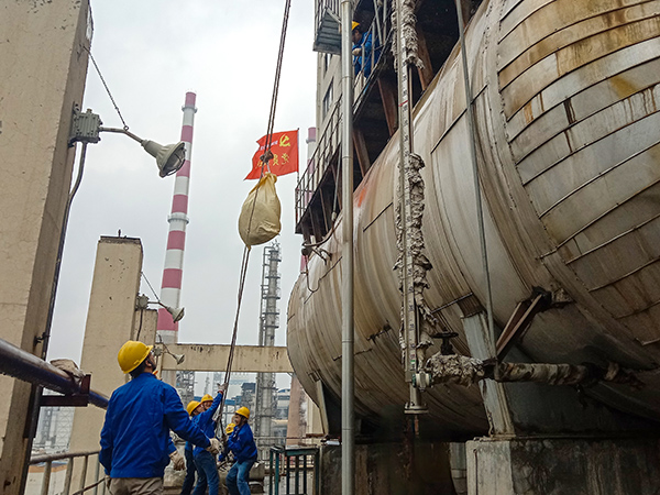 5月10日中午，在動力車間三期工藝除氧器地面，黨員突擊隊隊員用滑輪往工藝除氧器平臺運送鋼絲網(wǎng)，用以纏繞新填料.jpg